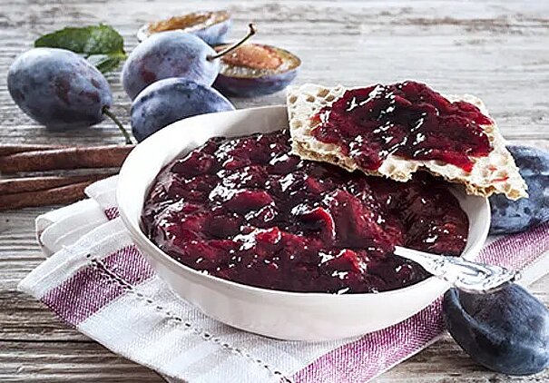 Ein runder Zwetschgenkuchen ist dicht mit Zwetschgenspalten und Mandelblättchen belegt.